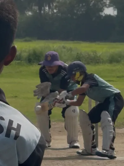 A view from behind the stumps, showing the batsman and wicket keeper in action.
