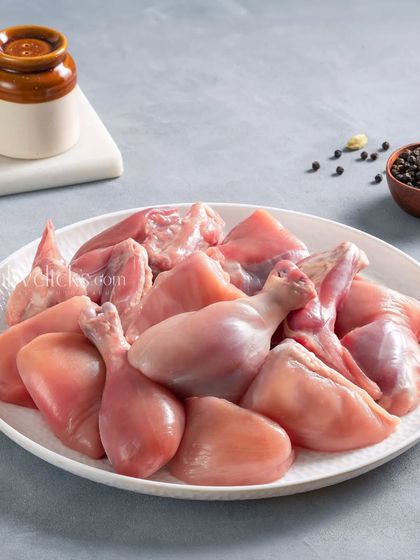 A plate of assorted raw chicken cuts, including drumsticks and thighs, shot on a clean, light-grey background for Zappfresh.