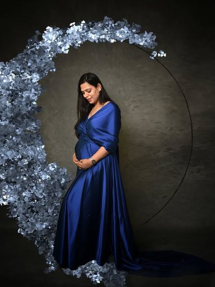This portrait uses a crescent of blue flowers to create a dreamy, celestial theme, celebrating the magical journey of motherhood.