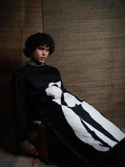 A slight variation in pose, this image continues the calm and artistic narrative. The focus remains on the unique graphic design of the longline shirt, perfect for a designer's conceptual lookbook.