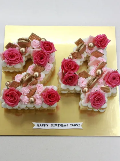 A beautiful number cake for a 24th birthday. This tart-style cake is shaped into the number "24" and decorated with cream, fresh roses, and macarons.
