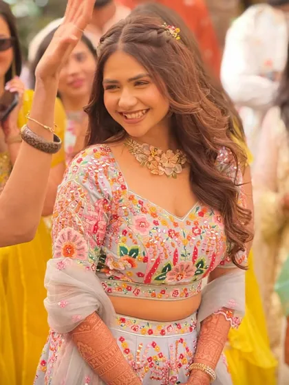 A candid shot of the smiling bride, her hair styled in a simple half-up twist with braids, allowing her to enjoy her Haldi ceremony without hair getting in the way.