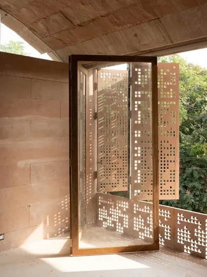 The play of light and shadow is essential. In the House of Solid Stone, we designed these operable, hand cut stone screens that modulate sunlight and privacy. This feature blends traditional craftsmanship with modern functionality, creating a living facade that breathes with the day.