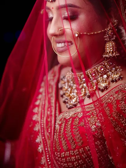 A close-up shot through a red veil, creating a vibrant and romantic bridal portrait.