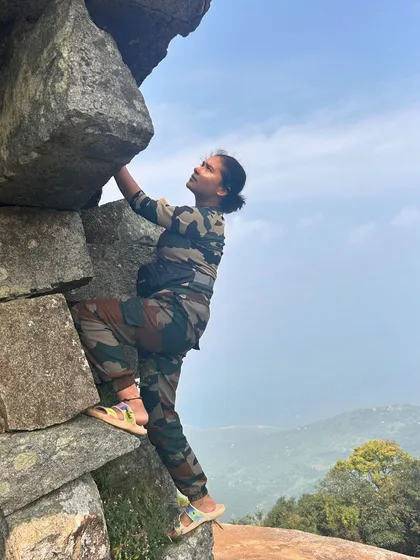 A trekker shows her strength, bouldering on the rocky path of the Skandagiri trail.