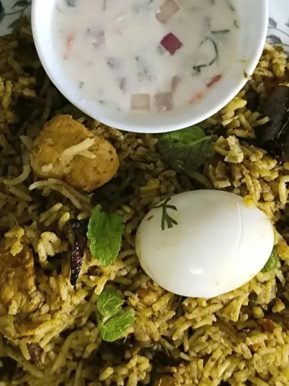 My Gongura Chicken Biryani is a tangy and spicy delight. The unique flavor of gongura (sorrel leaves) is infused into the tender chicken and rice, served here with a cooling raita.