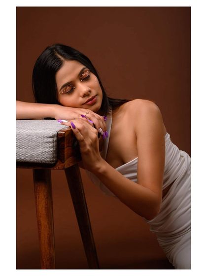A graceful and elegant studio portrait in a white dress. The model's pose is soft and fluid, creating a beautiful fashion image.