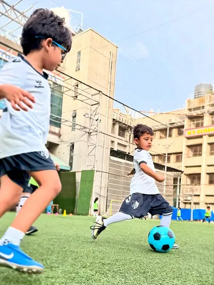 A young player makes a pass while his teammate runs into space, an early demonstration of the passing and movement we teach.