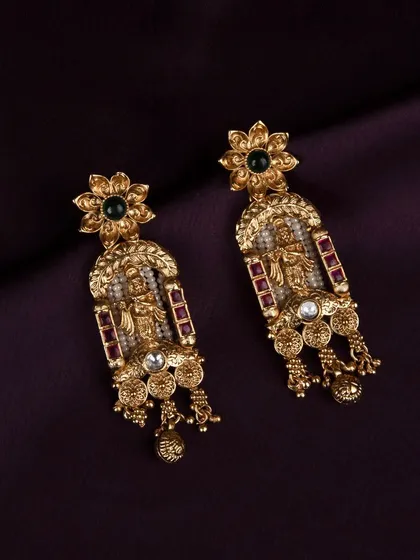 A detailed product shot of the traditional gold earrings, showcasing the intricate design with deity figures, rubies, and pearls against a dark purple background.