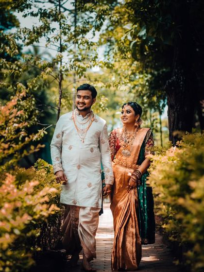 A beautiful portrait of a couple walking through a garden path, their traditional wedding attire complementing the natural surroundings.
