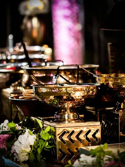 A traditional Indian buffet setup with ornate brass serving dishes. The warm glow of the metal adds a touch of royalty and heritage to the culinary spread.