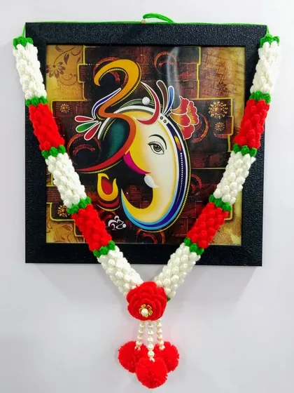 This Mogra Haar, inspired by delicate jasmine buds, is perfect for daily pooja. The classic red and white design brings a touch of traditional elegance to this photo of Ganpati Bappa, and it's completely washable and reusable.