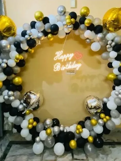 A modern and chic birthday balloon ring in black, white, silver, and gold. The neon sign adds a pop of light and a celebratory message.