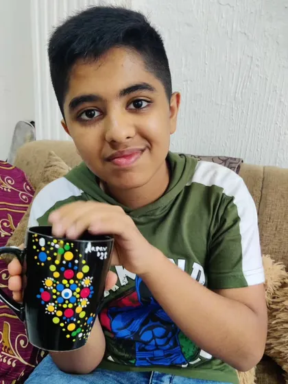 Another happy guest showing his completed dot art mug, a unique party favor he made himself.
