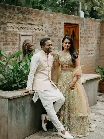 A couple poses by a stone fountain, the intricate details of the architecture providing a rich and interesting background.