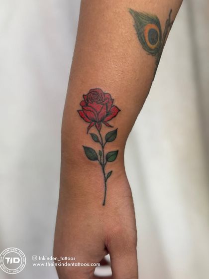 A classic and timeless red rose tattoo on the forearm. The vibrant color and clean line work make this a beautiful and elegant piece, symbolizing love and passion.