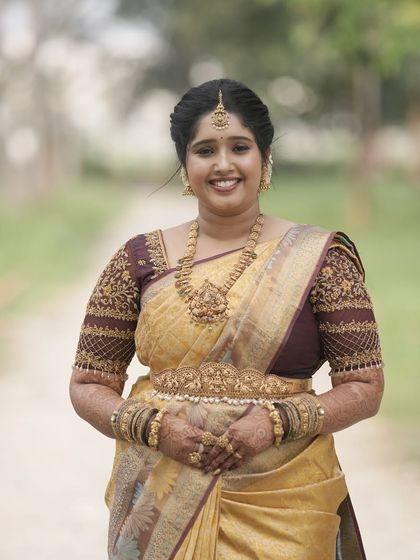 A full view of the bride's welcome look, featuring a beautiful golden-yellow saree and intricate jewellery.