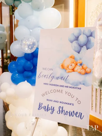 'We can bearly wait'. This adorable welcome sign for a teddy bear themed baby shower is surrounded by a cloud of blue and white balloons, setting a sweet and gentle tone for the event.