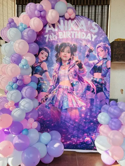 A K-Pop inspired birthday theme for a 7th birthday. The arched backdrop features the birthday girl's favorite characters, framed by a beautiful pastel balloon garland in shades of purple, pink, and blue.