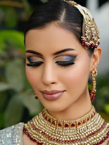 Eyes closed to show the beautiful blend of metallic blue and matte black eyeshadow, creating a stunning dual-tone effect.