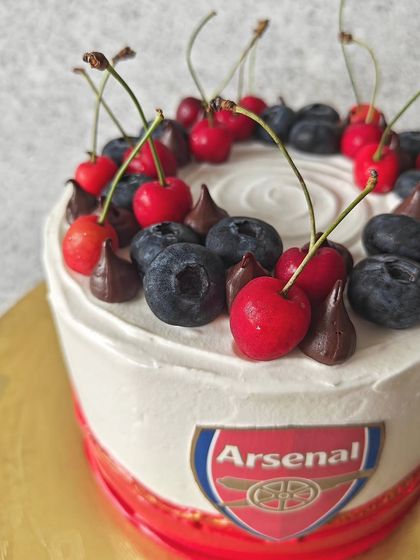 For the football fans, here's a cake I made for an Arsenal supporter. It's a Belgian chocolate cake decorated with the team's logo and topped with fresh cherries and blueberries.