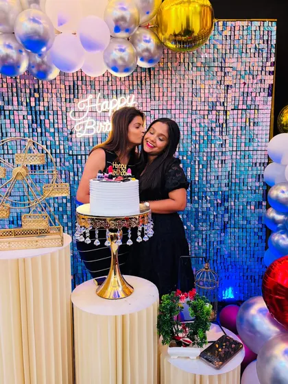 A sweet moment captured between friends during a birthday cake cutting. The sequin backdrop adds a touch of glamour to every photo.