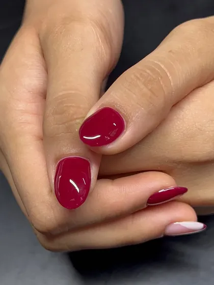 A classic red nail with a modern, abstract French tip accent.