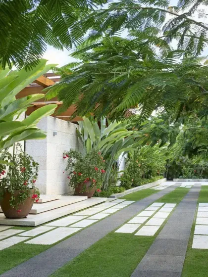 A modern driveway design using large stone pavers interspersed with strips of grass. This 'green driveway' approach is an eco-friendly and aesthetically pleasing alternative to solid concrete.