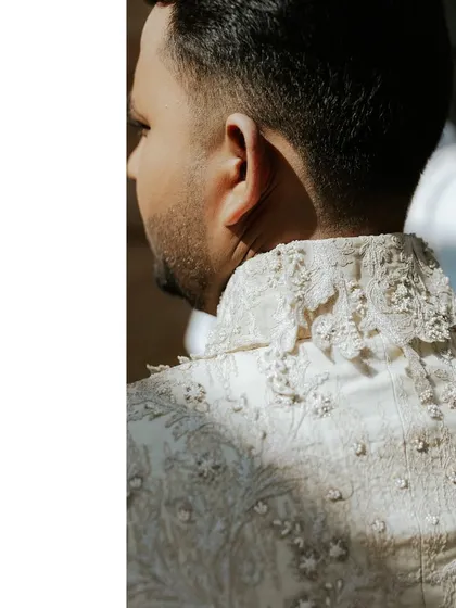 A look at the fine details of the groom's bespoke sherwani. The intricate embroidery on the collar shows the level of craftsmanship that went into creating his wedding day look.