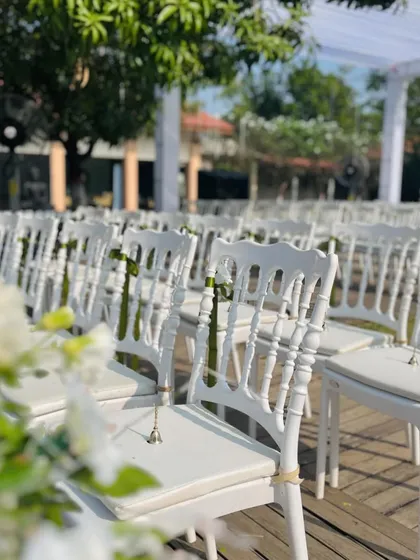 Elegant white Chiavari chairs lined up for the ceremony, each adorned with a small bell for guests to ring and wish the couple well.