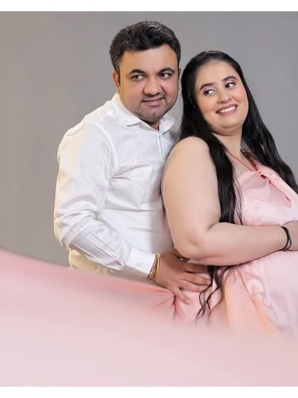 A happy and relaxed couple's portrait in the studio. The flowing pink fabric in the foreground adds a soft, dreamy touch to the photo.