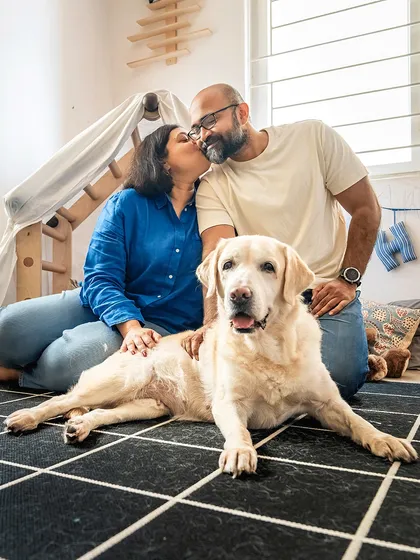 A beautiful family portrait celebrating their senior dog, Shelby. The couple shares a kiss while their beloved 10-year-old Labrador lies peacefully at the forefront.