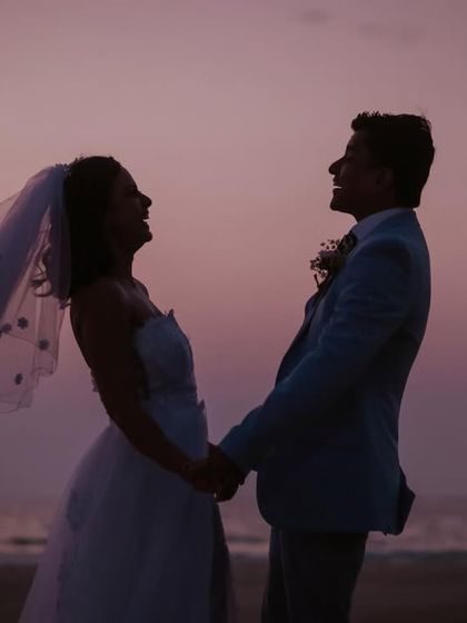 A silhouette filled with laughter. This candid shot captures the pure joy and happiness of the newly married couple on the beach at dusk.