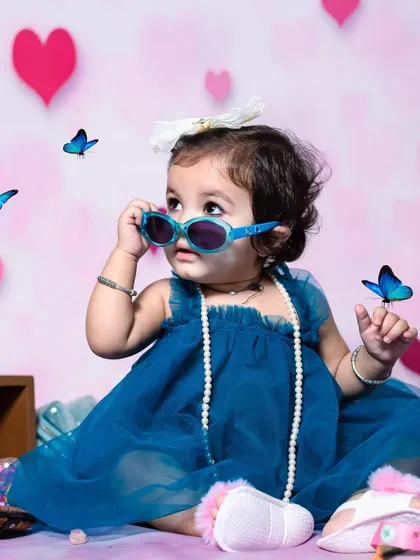 A little fashionista strikes a pose. With fun accessories like sunglasses and pearls against a heart-themed backdrop, we can capture your child's playful and stylish side.