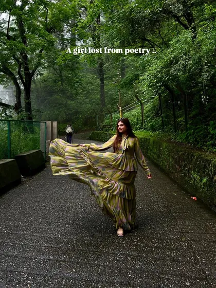 A girl lost in poetry. The flowing dress against the green, misty backdrop creates a dreamy and romantic image.