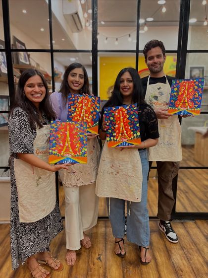 A group of friends who joined a public workshop together, showing off their colorful Eiffel Tower paintings. It's a perfect weekend activity for a group.