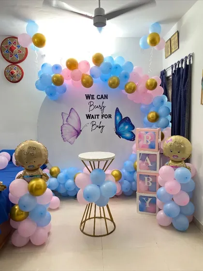 A classic gender reveal setup with a "We Can Bearly Wait for Baby" butterfly theme, using pink and blue balloons.