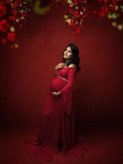 Looking up into a cascade of red flowers, this image creates a sense of magic and celebration around the mother-to-be.