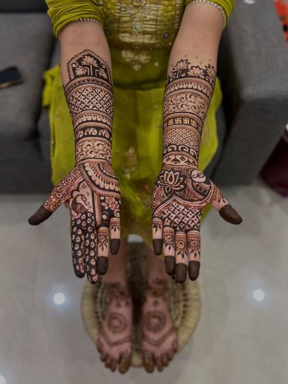 A top-down view of the full bridal mehendi, showcasing the detailed patterns on the hands and arms.