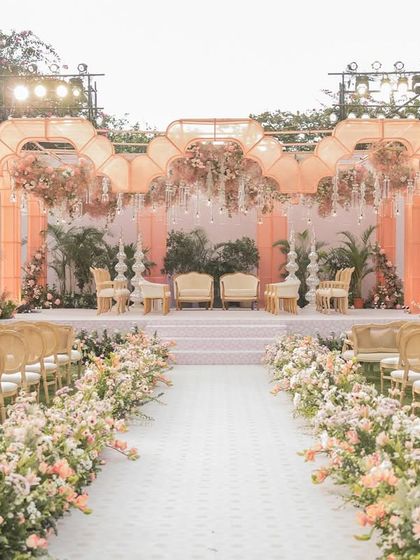 The full view of the 'Gulab Bagh' wedding aisle and mandap. The path is lined with lush flowers, leading to the glowing organza structure for a dramatic and romantic effect.