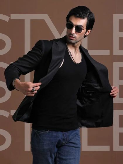 A classic black blazer, shown with a casual black tank top and jeans. This demonstrates the power of a perfectly tailored jacket to elevate even the simplest outfit.