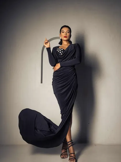 A full-length shot for Roologyofficial, showcasing a classic glam look with a bold red lip and a sophisticated updo. The flowing dress and confident pose are enhanced by the timeless makeup and hair.