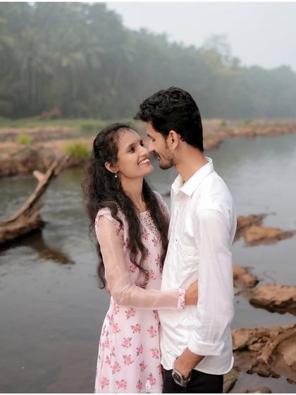 An intimate gaze shared between the couple, with the rocky riverbed and misty forest creating a wild, romantic backdrop.