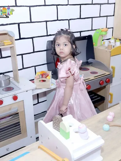 A little guest takes a break from the party to cook up some fun in our pretend play kitchen.