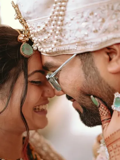 A close-up filled with laughter, capturing the bride's hand on the groom's face, showcasing their deep affection.