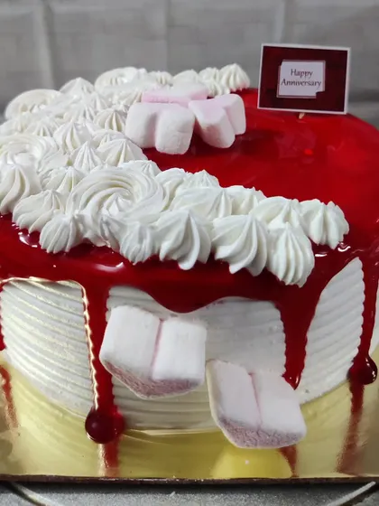 A red drip cake with fluffy white piping and marshmallows. A fun and playful design for an anniversary.