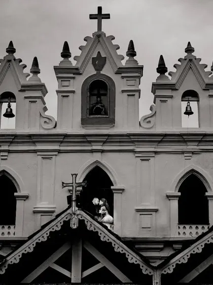 A creative composition framing the couple's kiss within a church window. This black and white shot uses the building's architecture to create a unique, layered portrait that feels both grand and intimate.