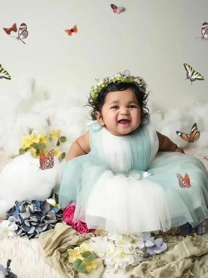 A big, happy grin from the star of the show. Her joy is infectious in this beautifully styled six-month photoshoot, surrounded by flowers and fluttering butterflies.
