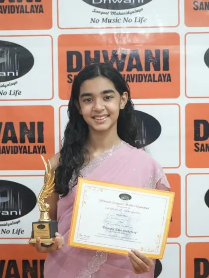 A student poses gracefully with her certificate and trophy.