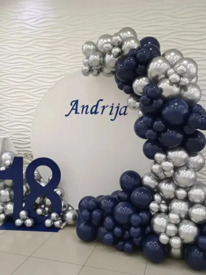 A personalized 18th birthday with a custom name backdrop and a balloon arch in navy blue and chrome silver.
